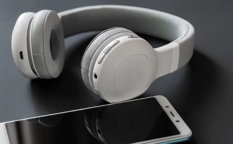 モバイル・音響(スマホ、PC等) ヘッドフォンとスマホが横に並んでいる様子