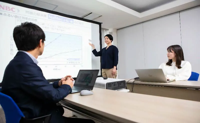 a picture of a standing woman in a suit giving a presentation to a sitting man in a suit Photographs of comparing liquids in test tubes, taking notes, verifying and analyzing them