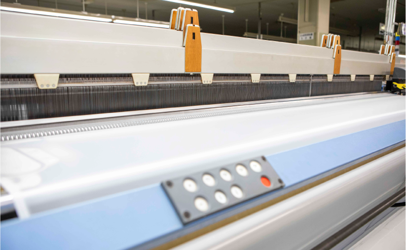 A view of mesh being manufactured on a loom.