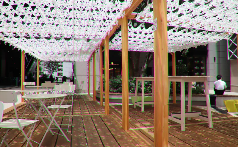 Photo of a fractal sunshade installed on a wooden deck with tables and benches