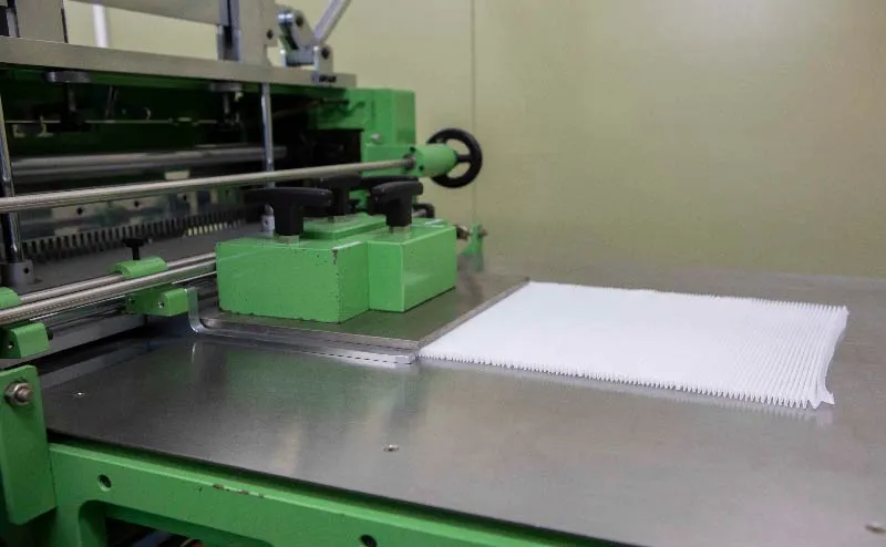 Pleating machine. Pleated mesh is coming out of the machine.