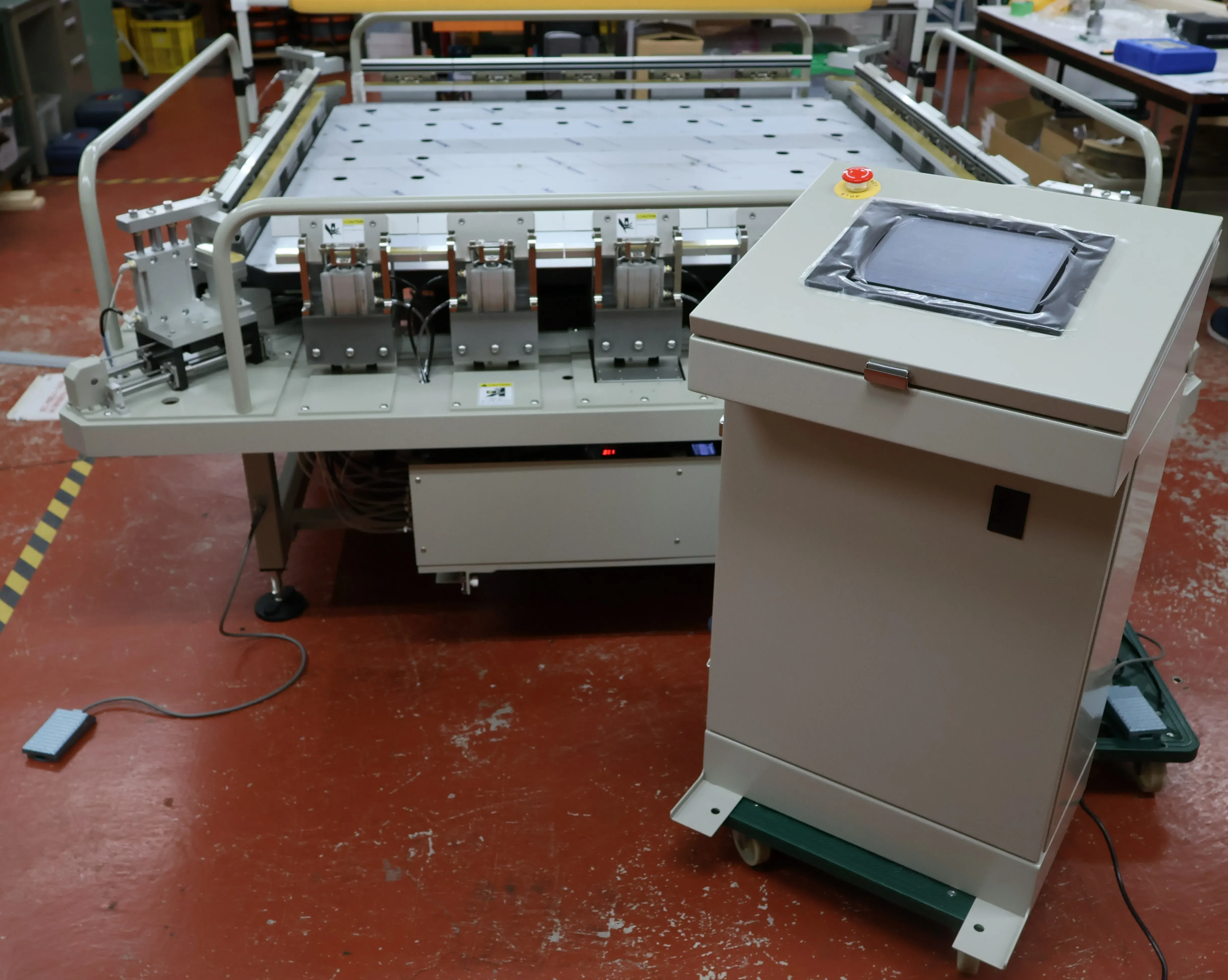 Photograph of a high-precision semi-automatic gauze stretcher with the operation panel in the foreground and the gauze stretcher itself in the background.